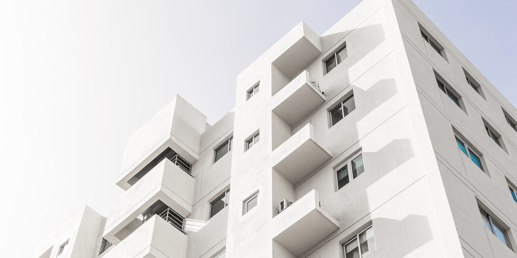 Low angle shot of a facade of a white modern building under a blue clear sky